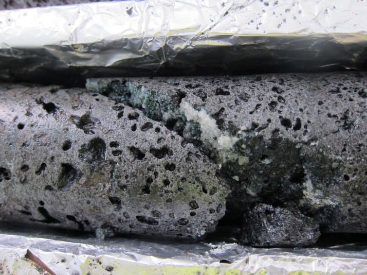 The fracture in this basalt rock shows the white calcium carbonate crystals that form from the injection of CO2 with water at the test site. Credit: Annette K. Mortensen
